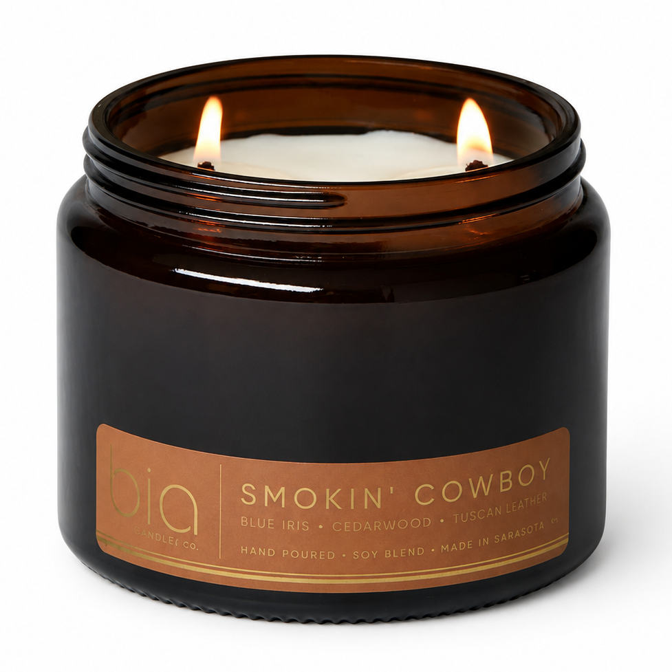 Amber glass soy candle jar with two lit flames and orange-tan label