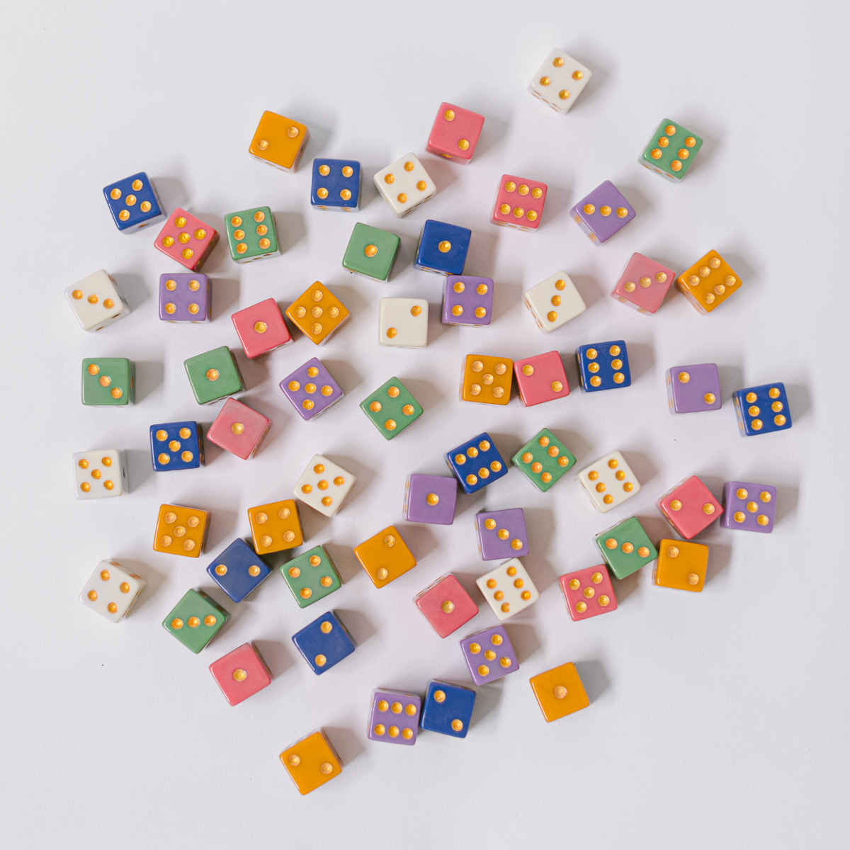 Assorted multicolor dice scattered on a light surface.
