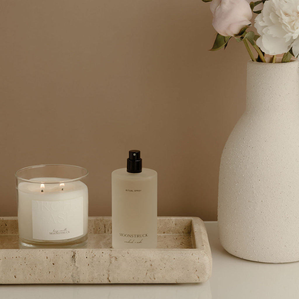 MOONSTRUCK Ritual Spray frosted bottle with black pump cap on tray, with candle.
