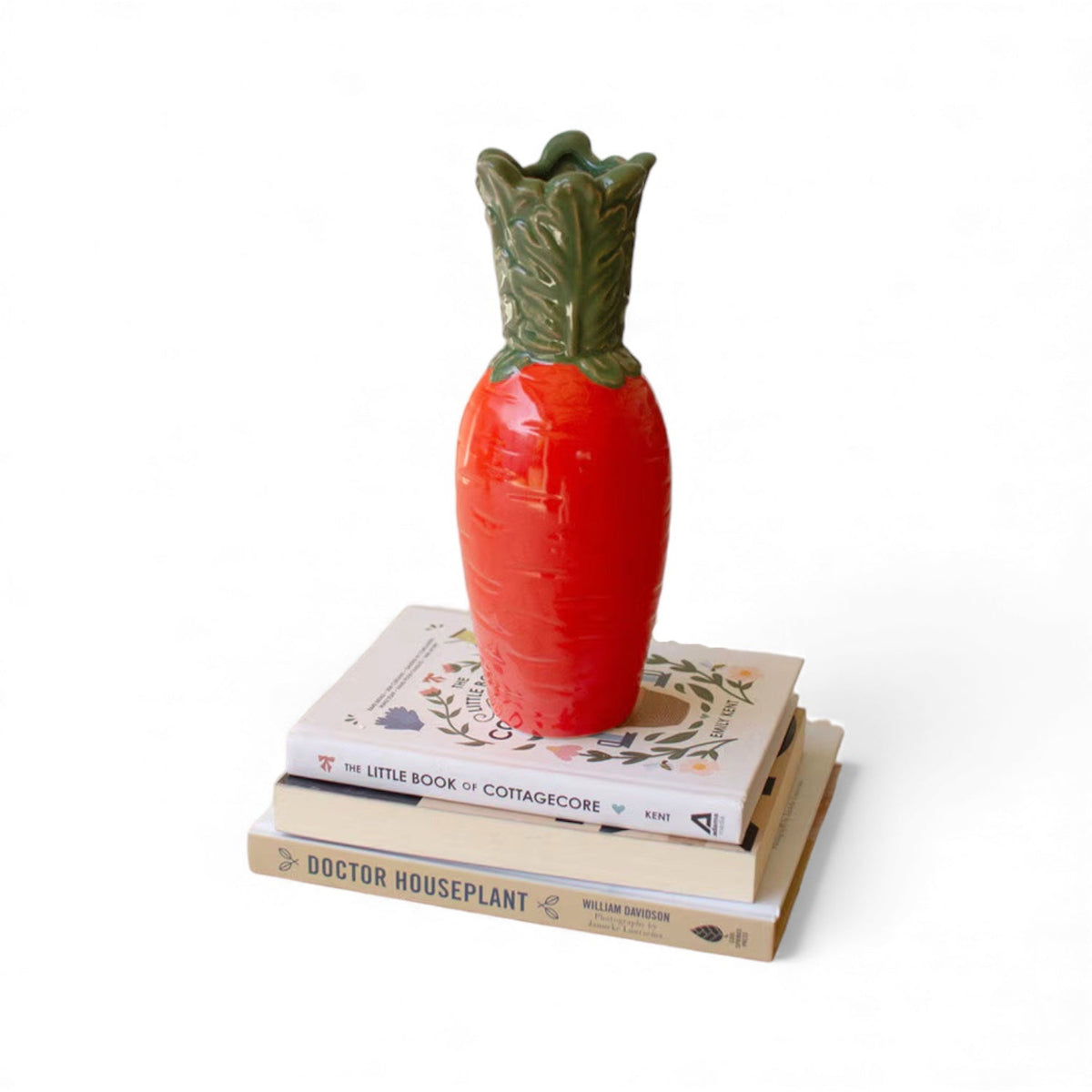 Orange ceramic carrot vase with green ridged leaves