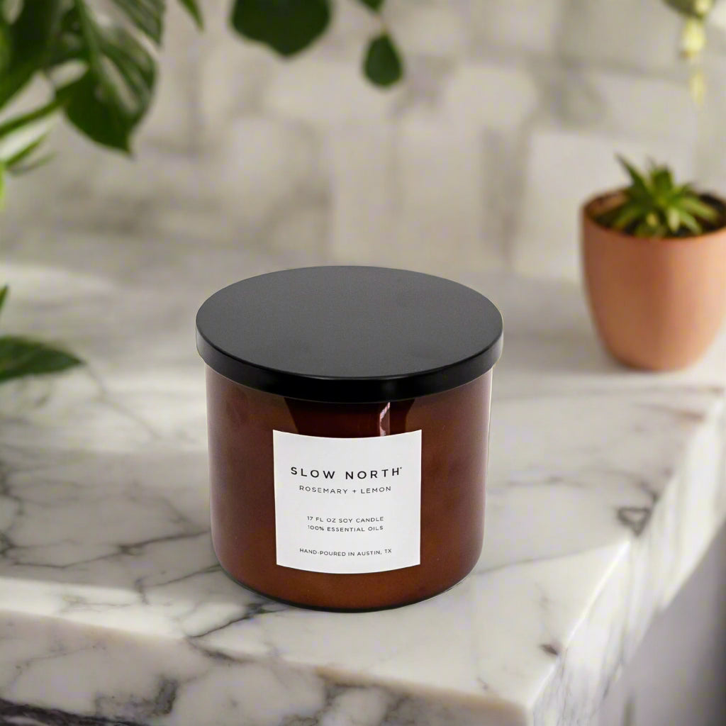 Brown 3-wick soy candle in glass jar with black lid closed and front label