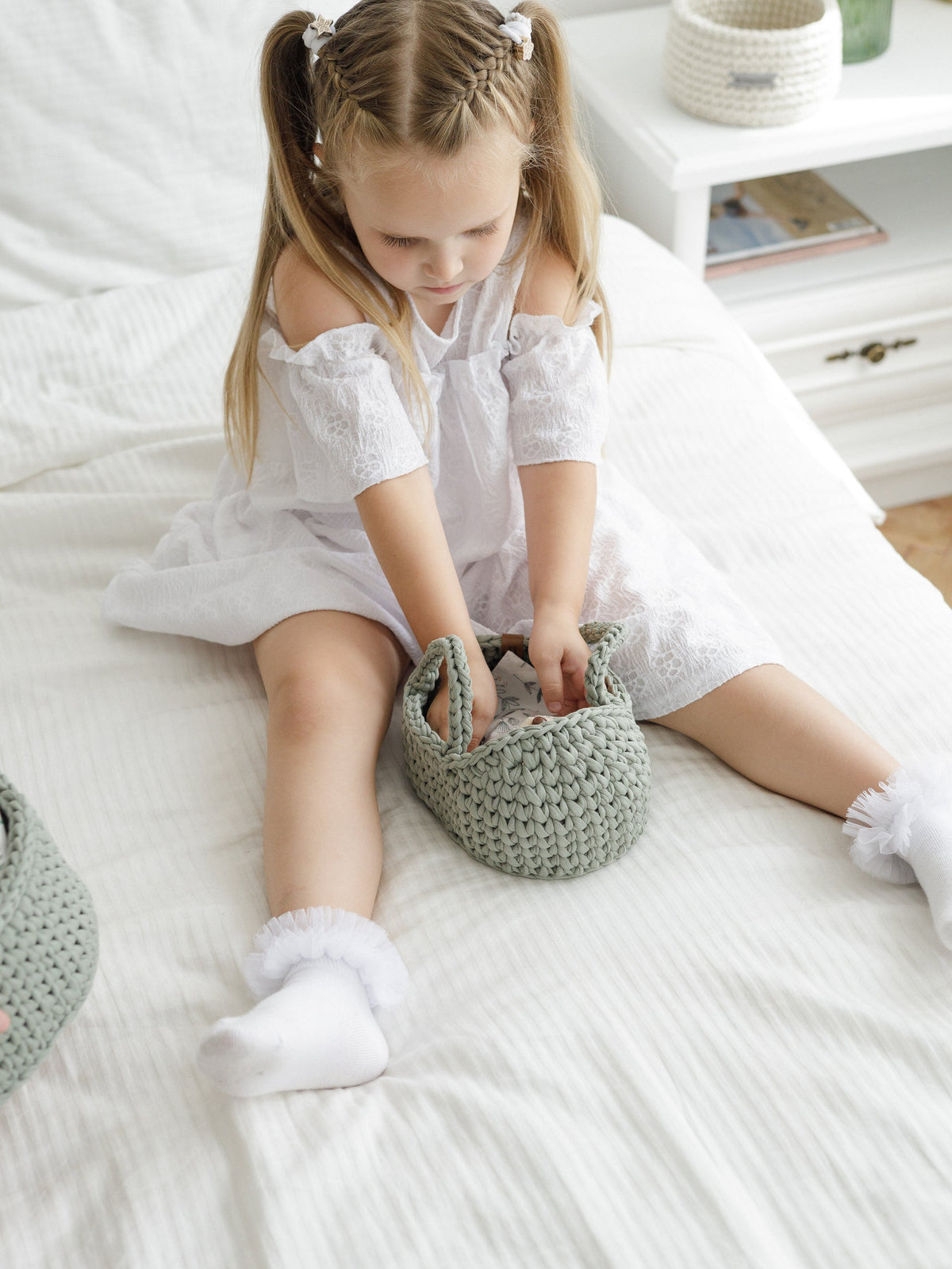 Mini doll Moses basket, sage green knitted basket on a bed