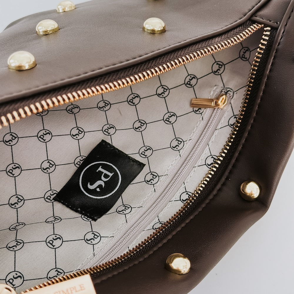 Brown bum bag interior with logo patch, patterned lining, and gold-tone zippers