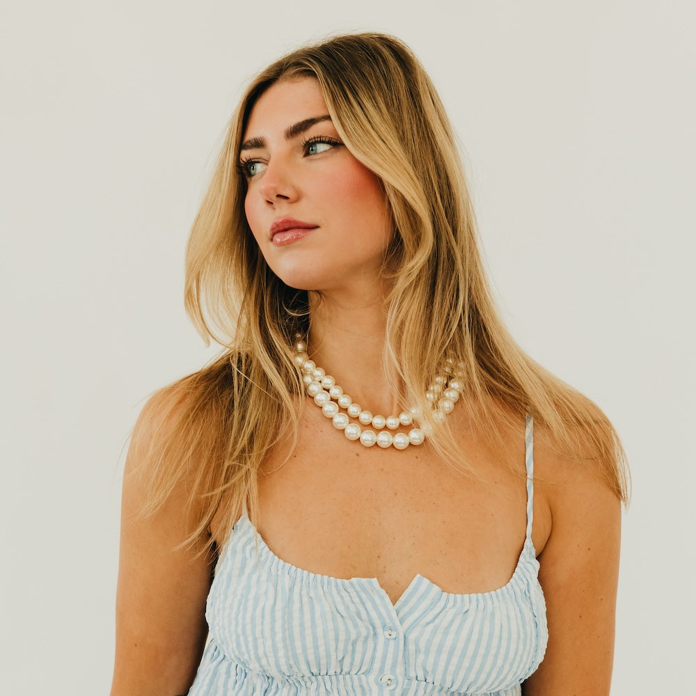 Chunky pearl three-row necklace worn on model, white pearls with gold-tone clasp