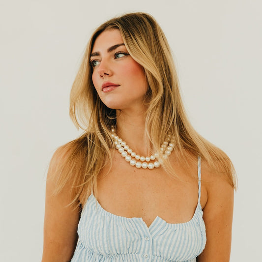 Chunky pearl three-row necklace worn on model, white pearls with gold-tone clasp