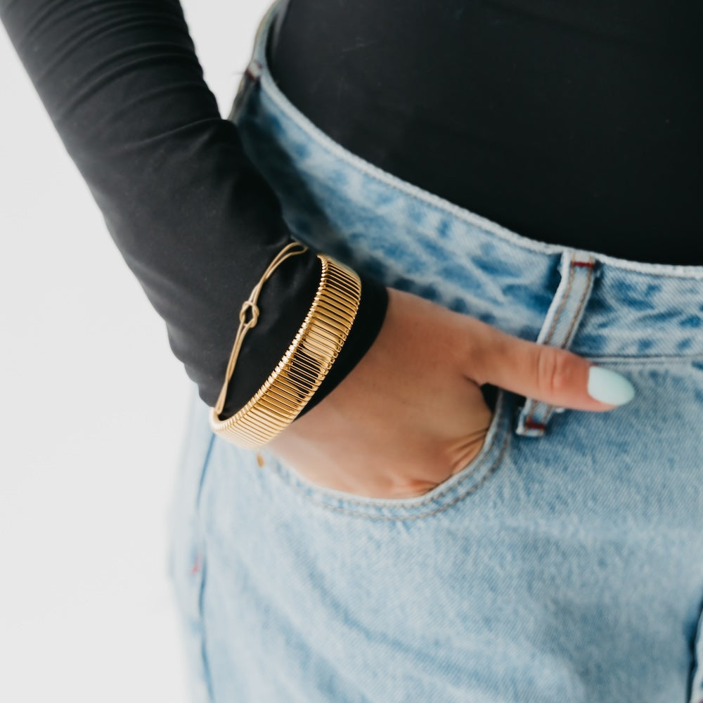 Ribbed gold chunky bangle bracelet on wrist with hinge clasp