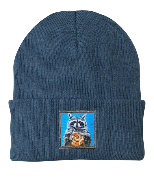 Heather blue knit beanie with embroidered raccoon graphic patch centered on cuff