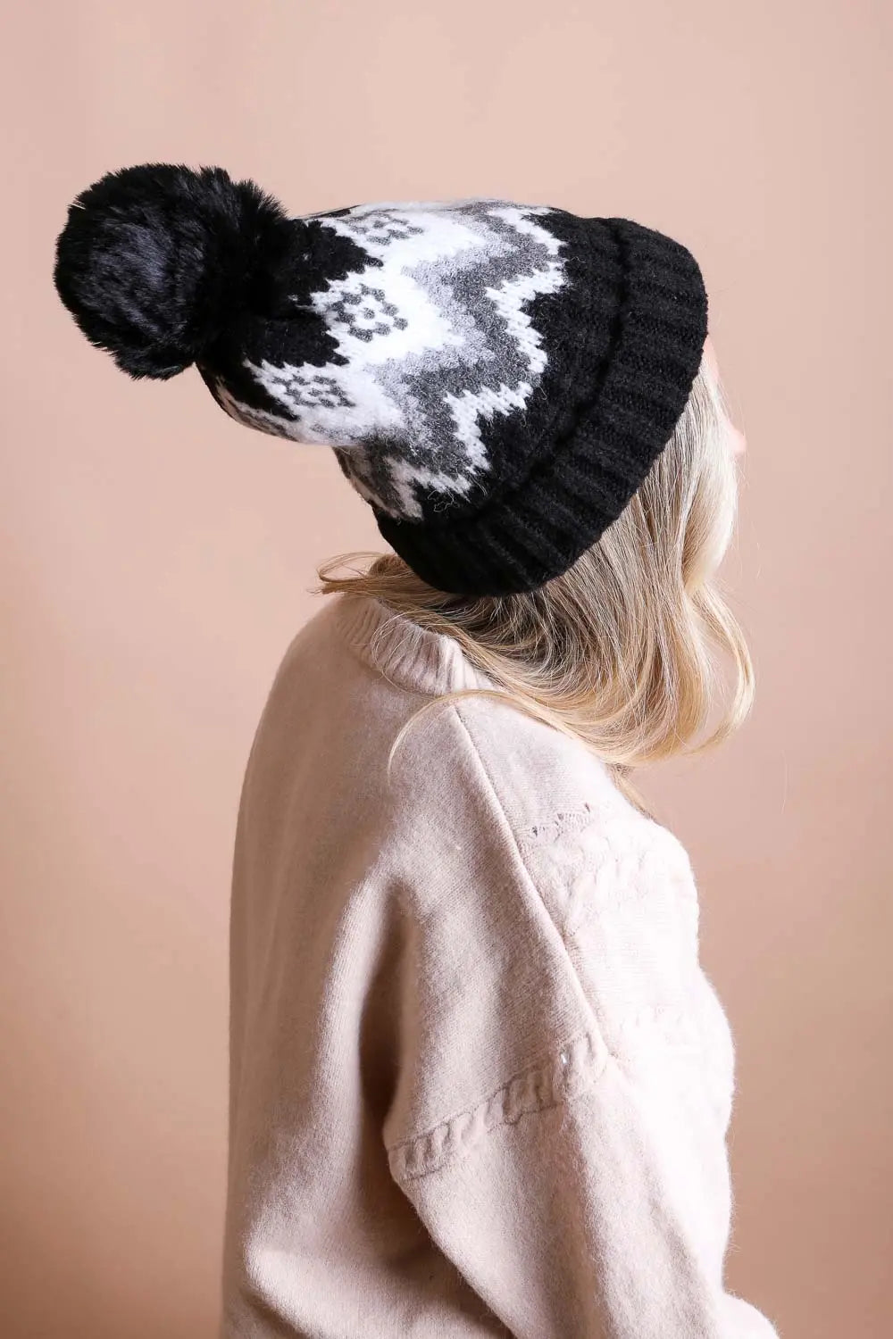 Black knit winter beanie with white geometric fair isle pattern and black pom-pom