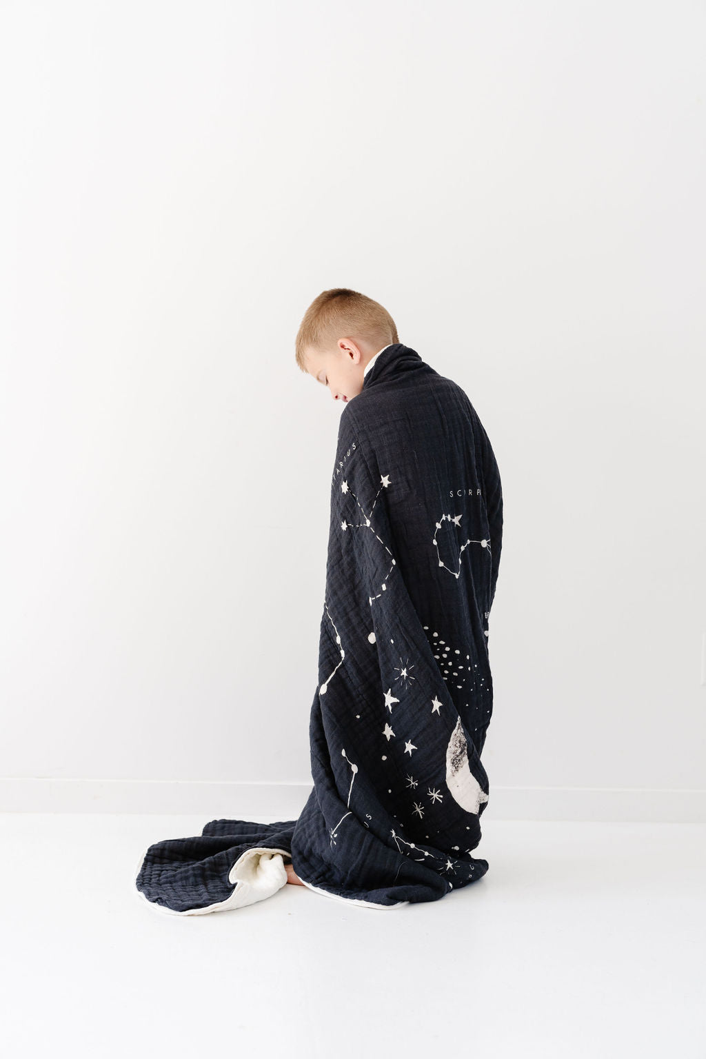 Navy starry astrology blanket draped on floor, moon and constellation prints visible