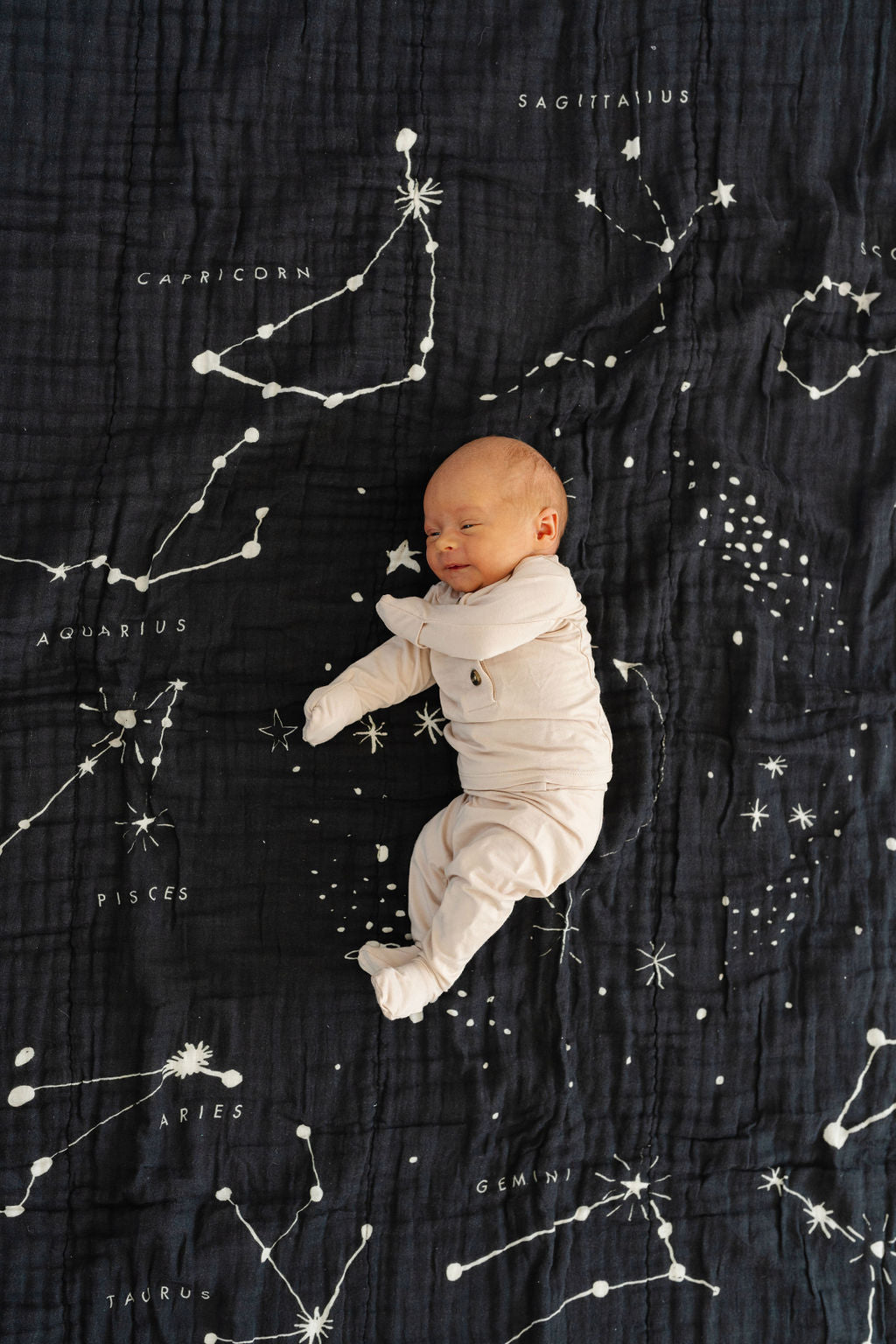 Black astrology blanket close-up with scattered constellation lines and moon graphic