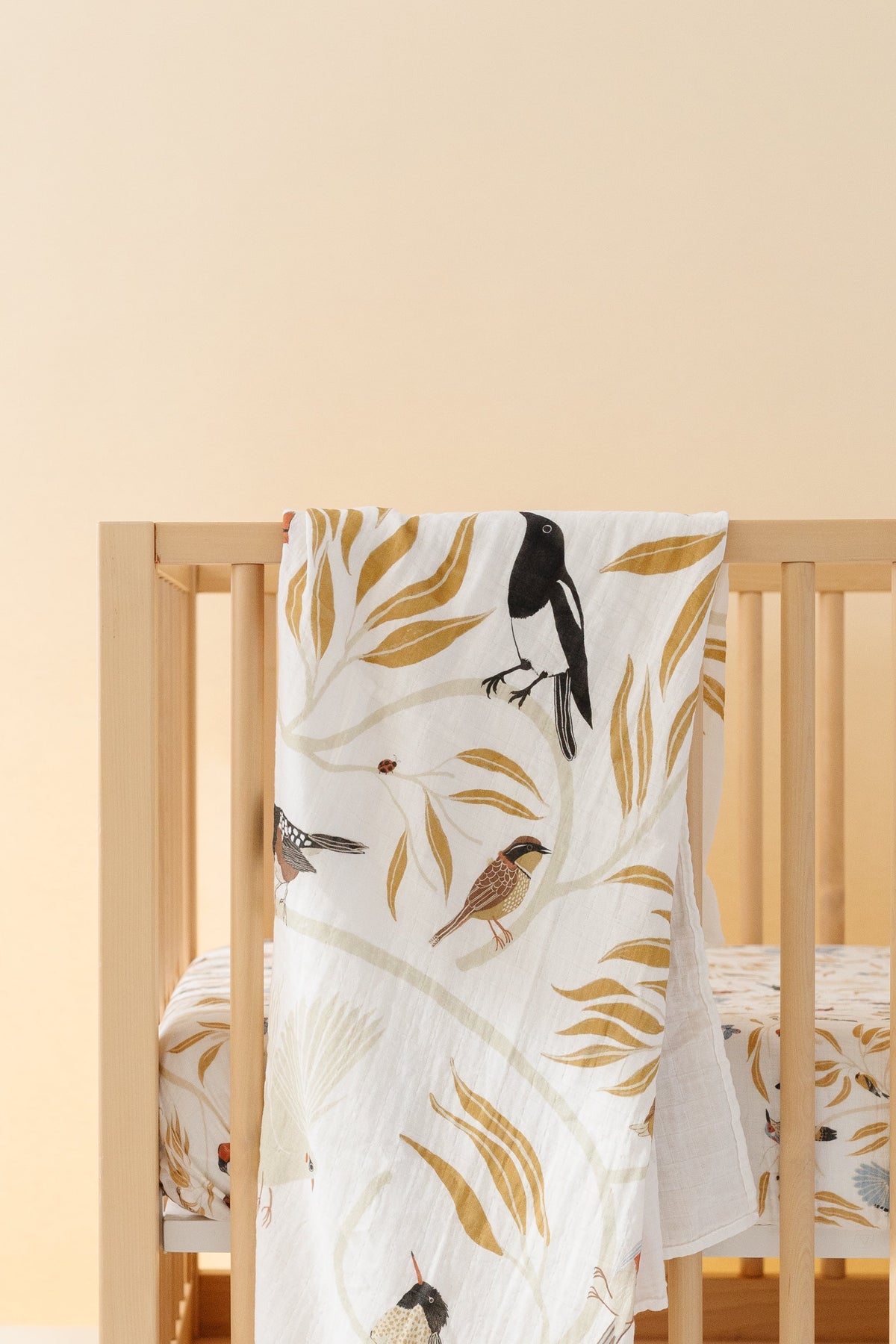 Swaddle blanket with white background and illustrated birds with yellow leaf patterns