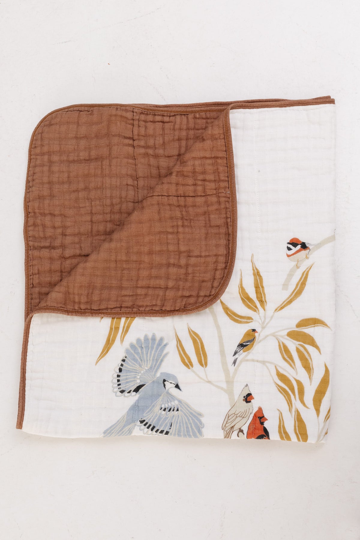 Folded baby quilt: white bird print front with brown solid back panel