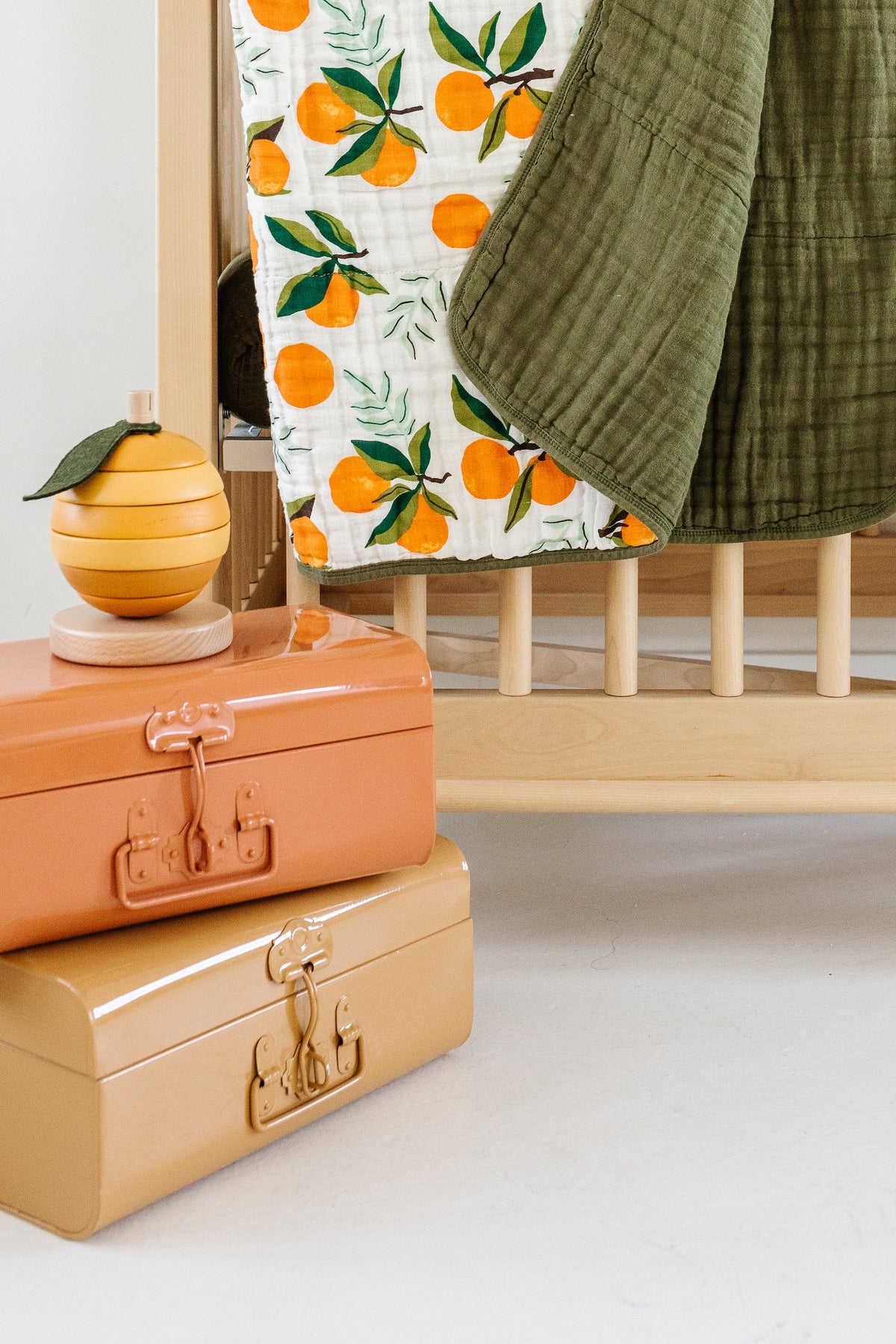 Clementine quilt throw draped with orange fruit print and olive-green border