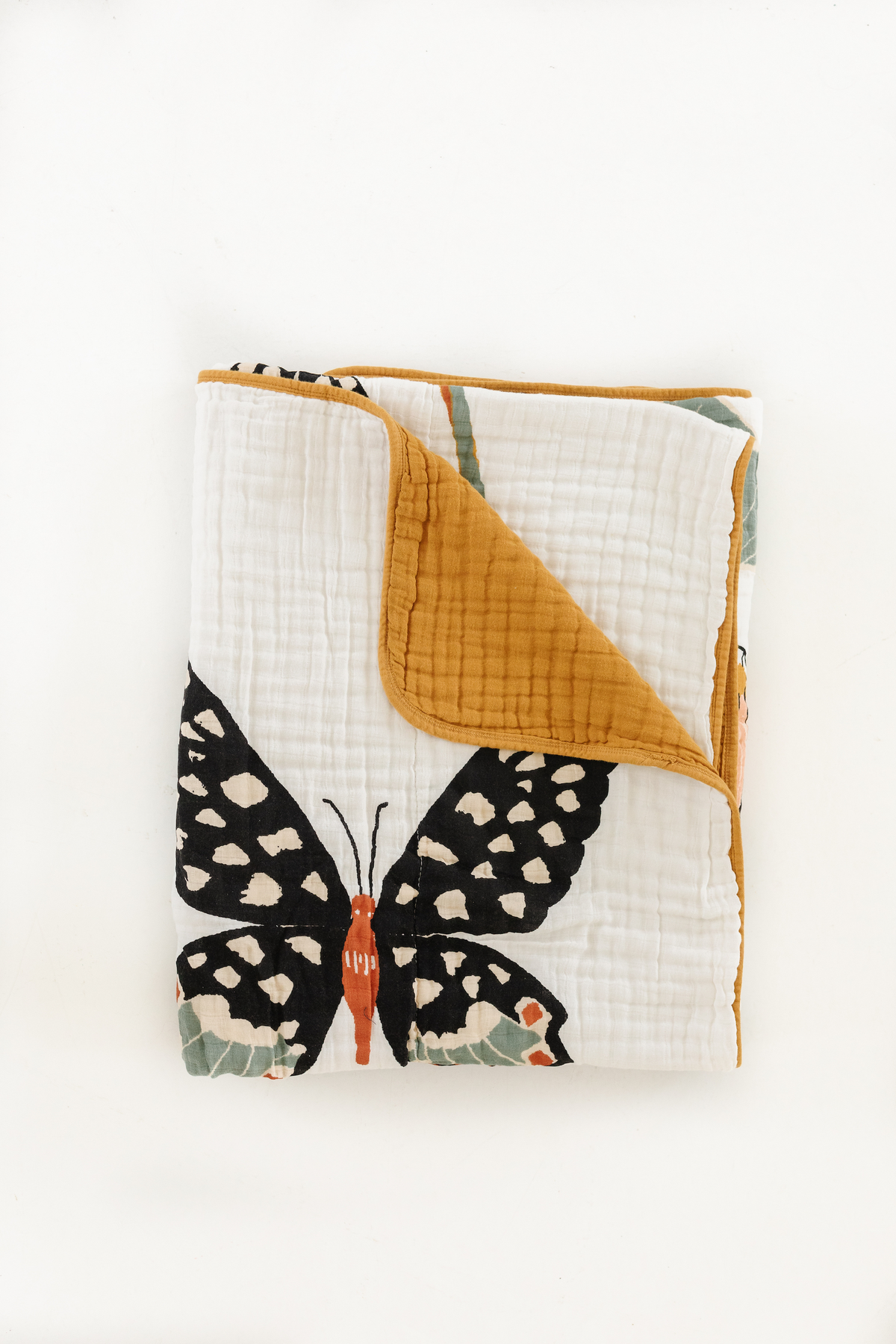 White reversible throw blanket folded flat, butterfly print with mustard-yellow trim