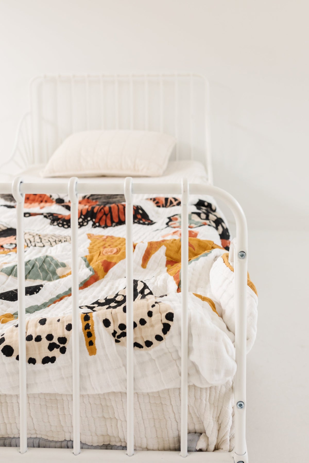 White butterfly throw blanket draped on bed, mustard border on quilted fabric