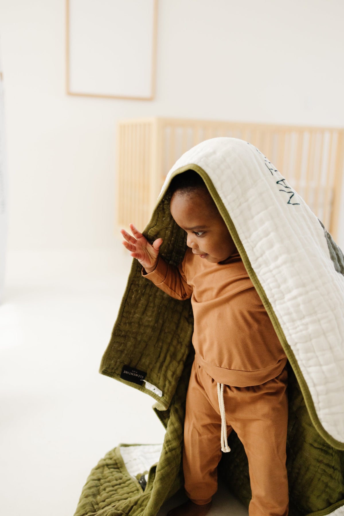 White quilted blanket with national park print, draped as a hood over a child.
