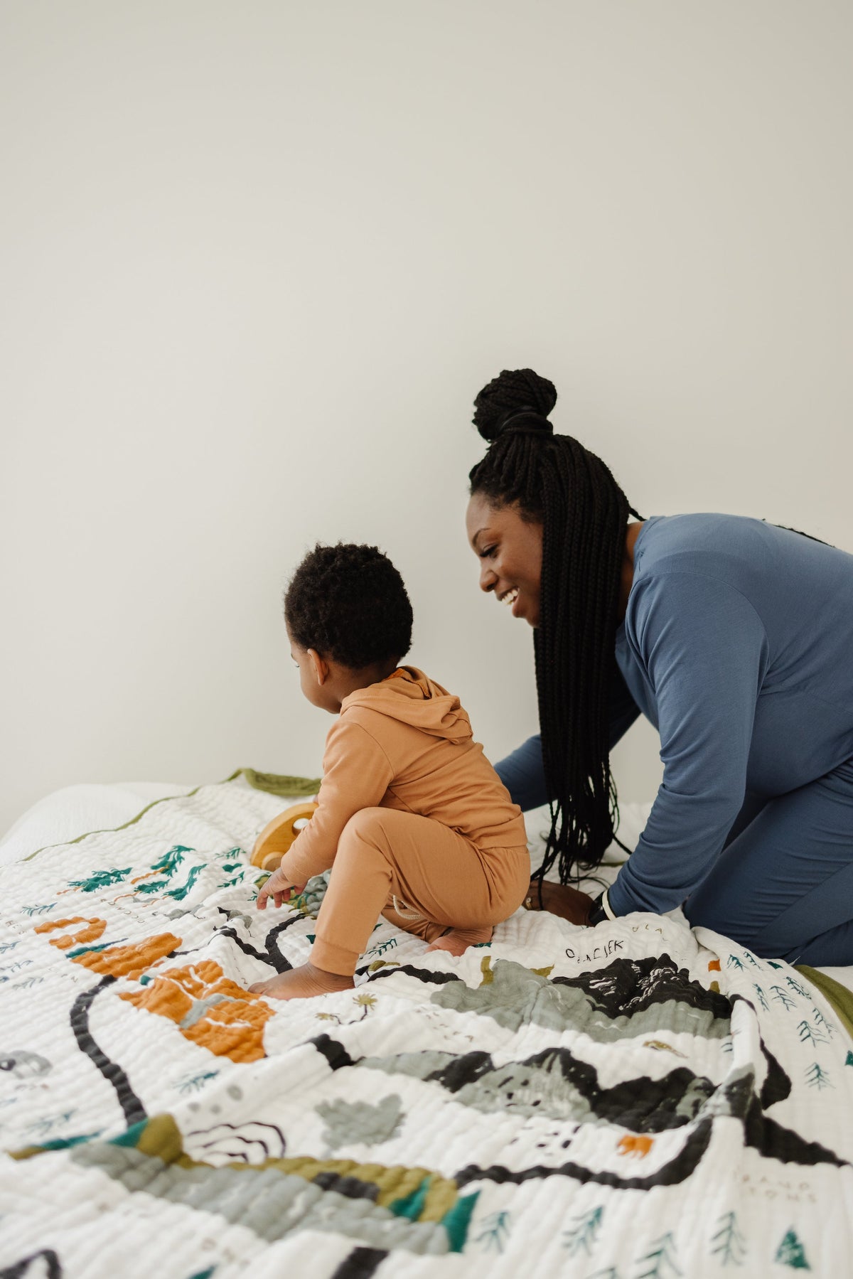 Quilted white throw blanket with national park landscape: green trees and orange details.