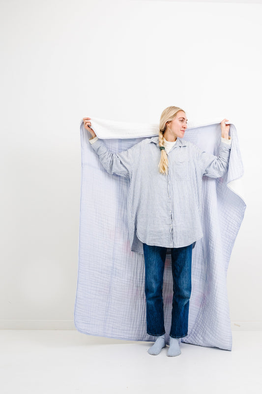 Light blue quilted throw blanket with draped edges and textured weave