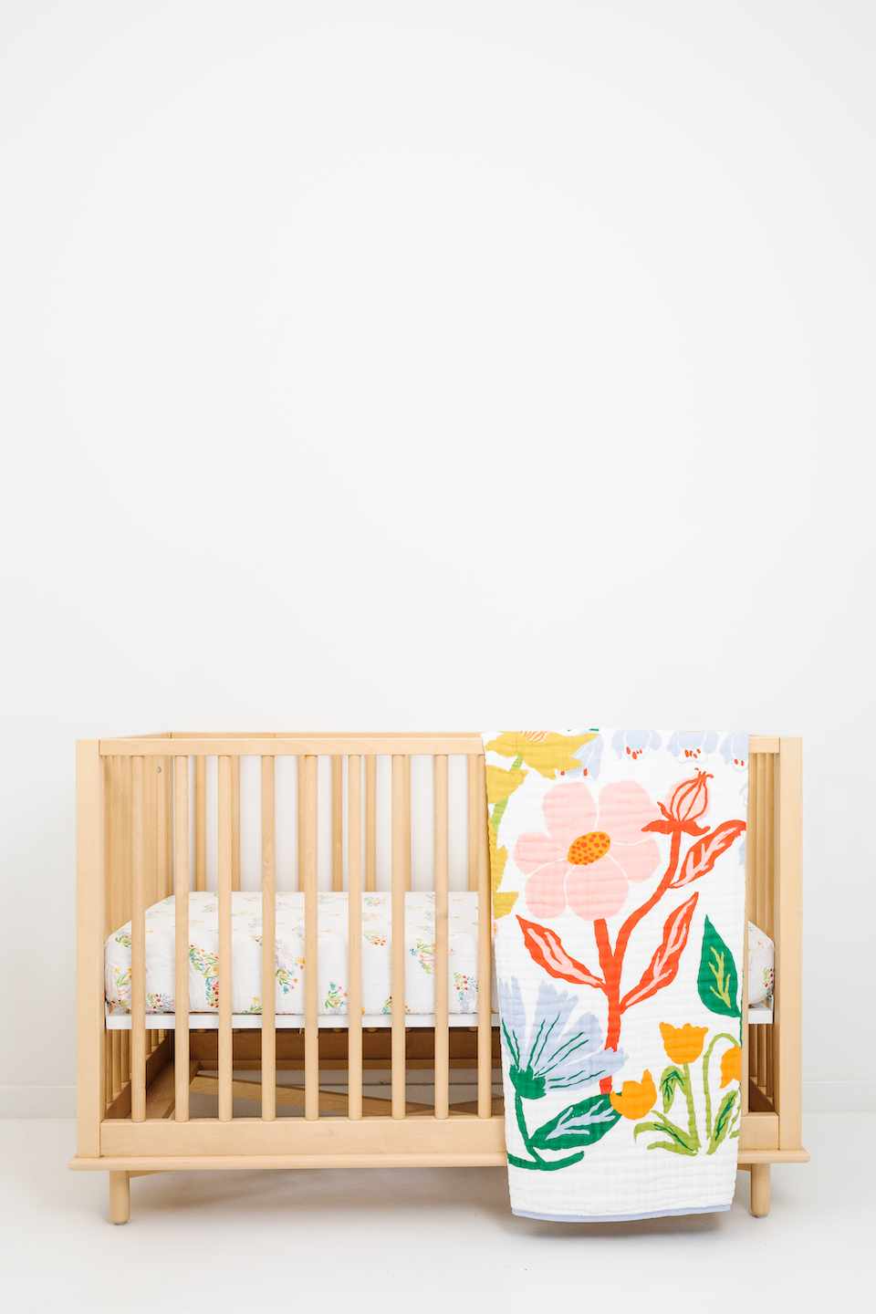 Kids quilt over wooden crib with full botanical print on white background