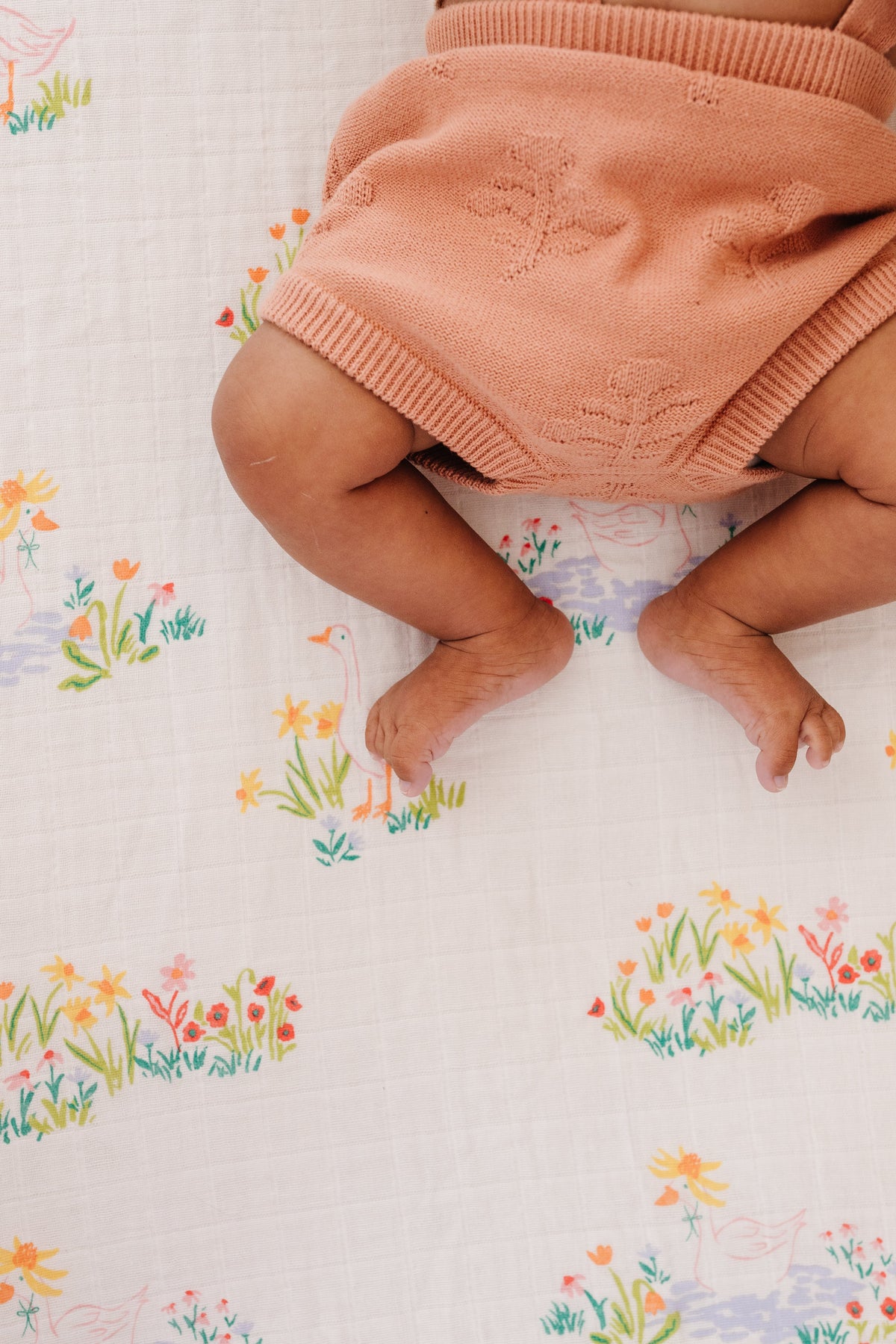 Close view of patterned crib sheet with pastel geese and wildflowers.