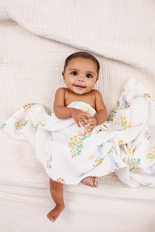 Garden goose swaddle blanket on baby, white muslin with colorful garden animal print