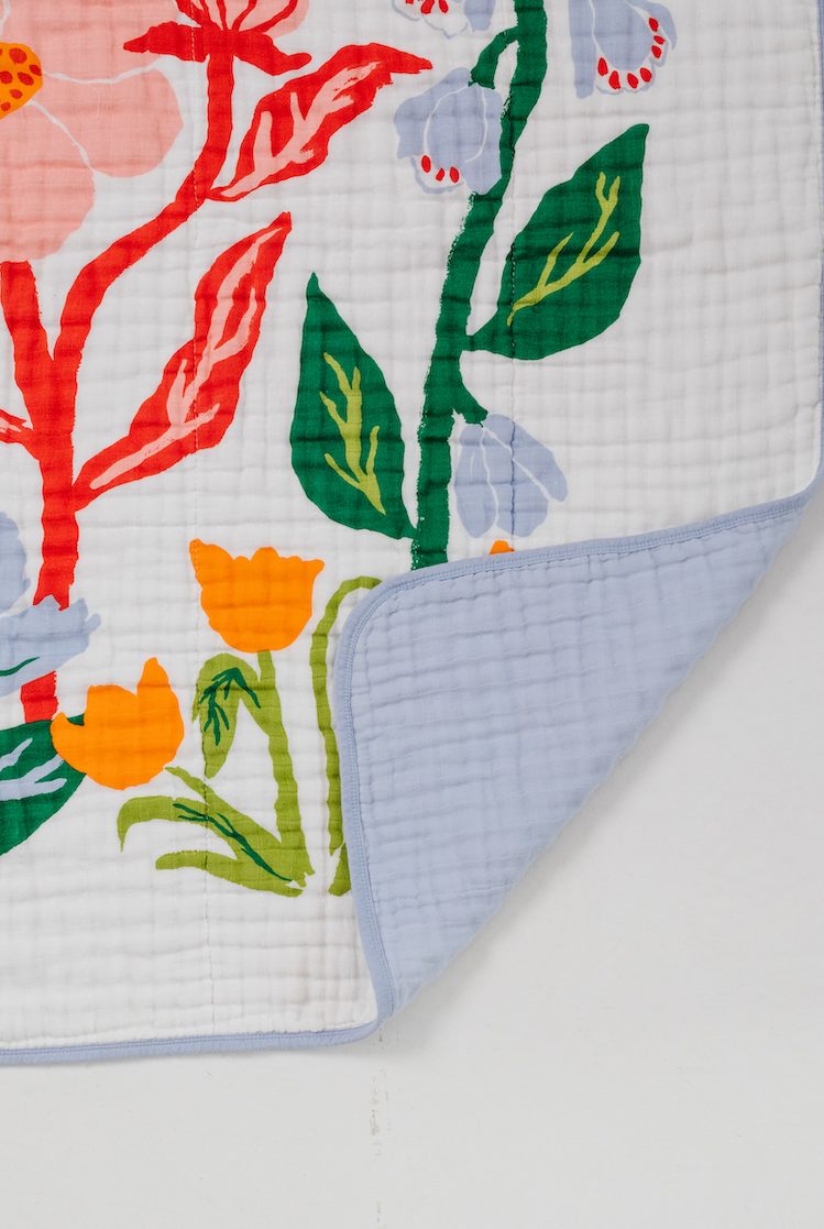 Light blue quilt backing and white front panel with colorful leaf and blossom print