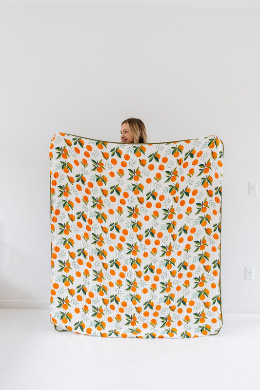 White quilted throw blanket with orange clementine and green leaf print