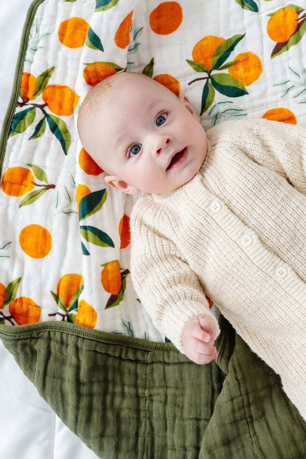 Clementine quilt blanket showing orange fruit print and olive-green edging