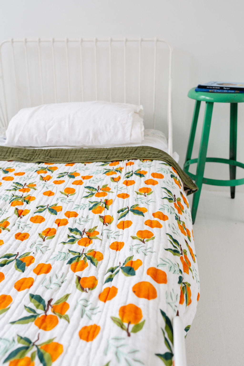 Quilted throw blanket on bed with white base and orange clementine pattern