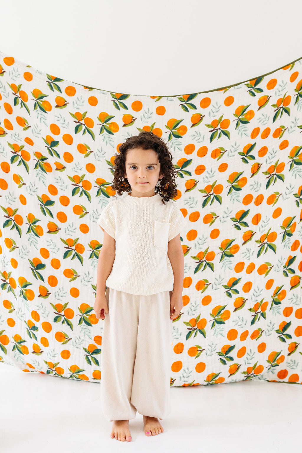 White clementine print throw blanket with orange fruit and green leaves