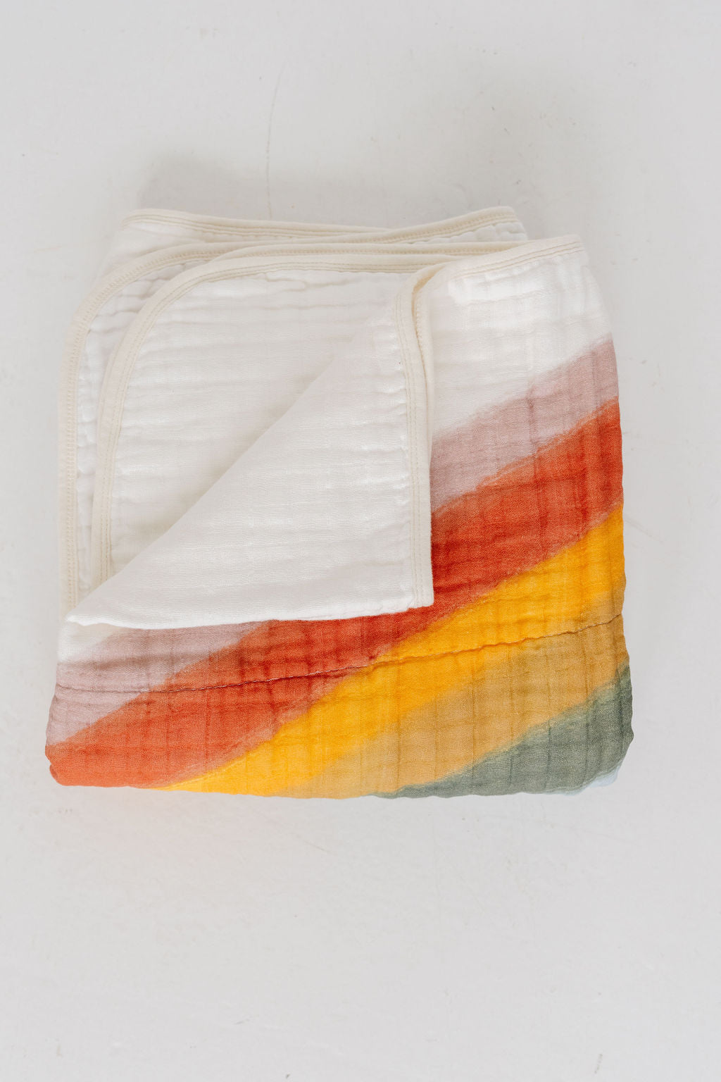 Folded rainbow quilt with orange, yellow, green, blue, and purple stripes