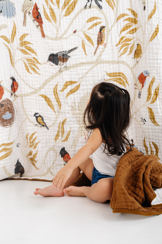 Bird print throw blanket on cream fabric with gold leaves and multicolor birds