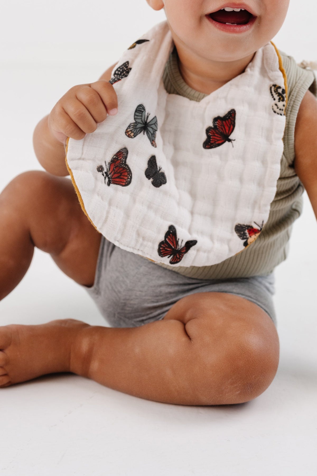 Baby bib in white muslin with multicolor butterfly prints and tan trim