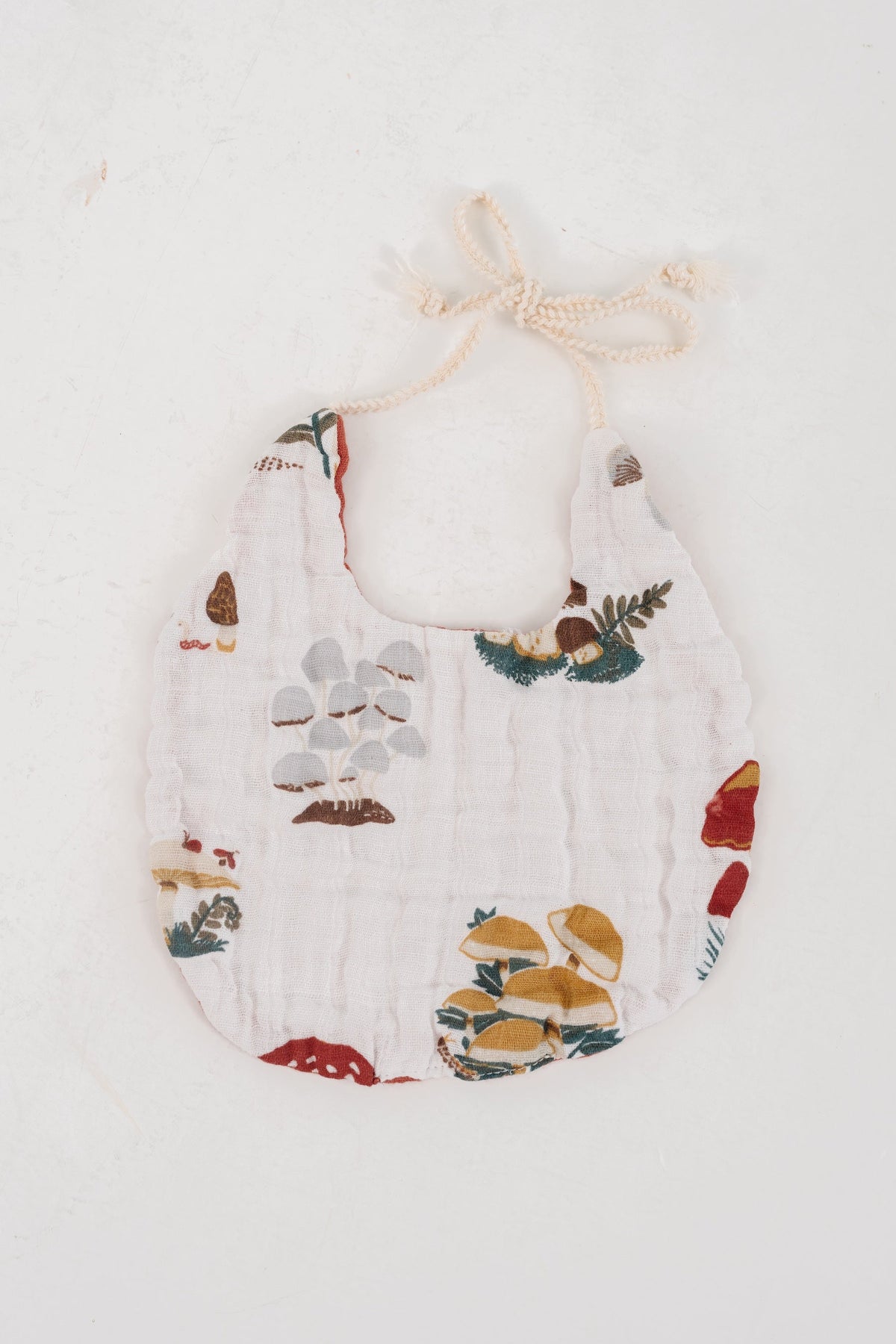 White bib with scattered mushroom illustrations and tied neckline