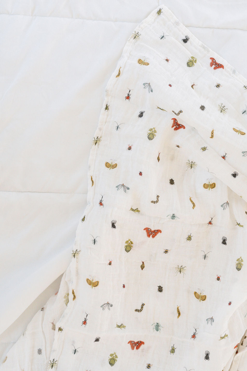 White baby swaddle blanket corner with small animal print on quilted fabric