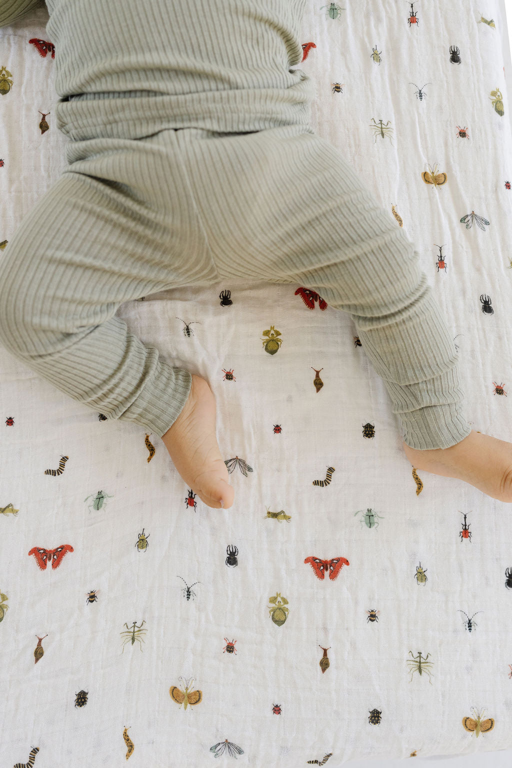 Crib sheet with gathered fabric showing colorful insect print