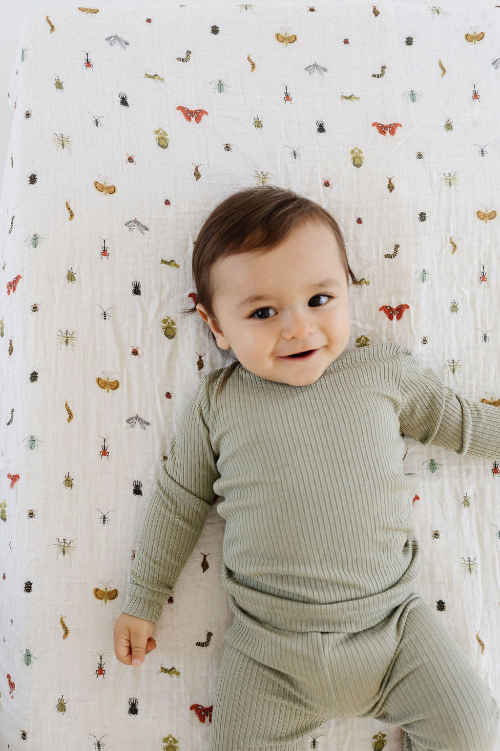 Light patterned crib sheet with colorful insect and bug illustrations