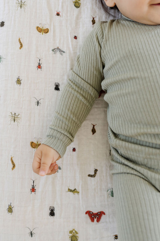 Fitted crib sheet corner with colorful crawling insect pattern