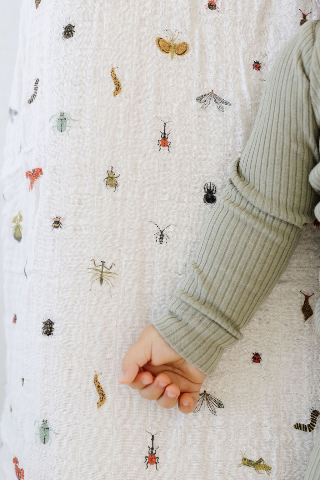 Crib sheet showing multicolor bug print and folded corner
