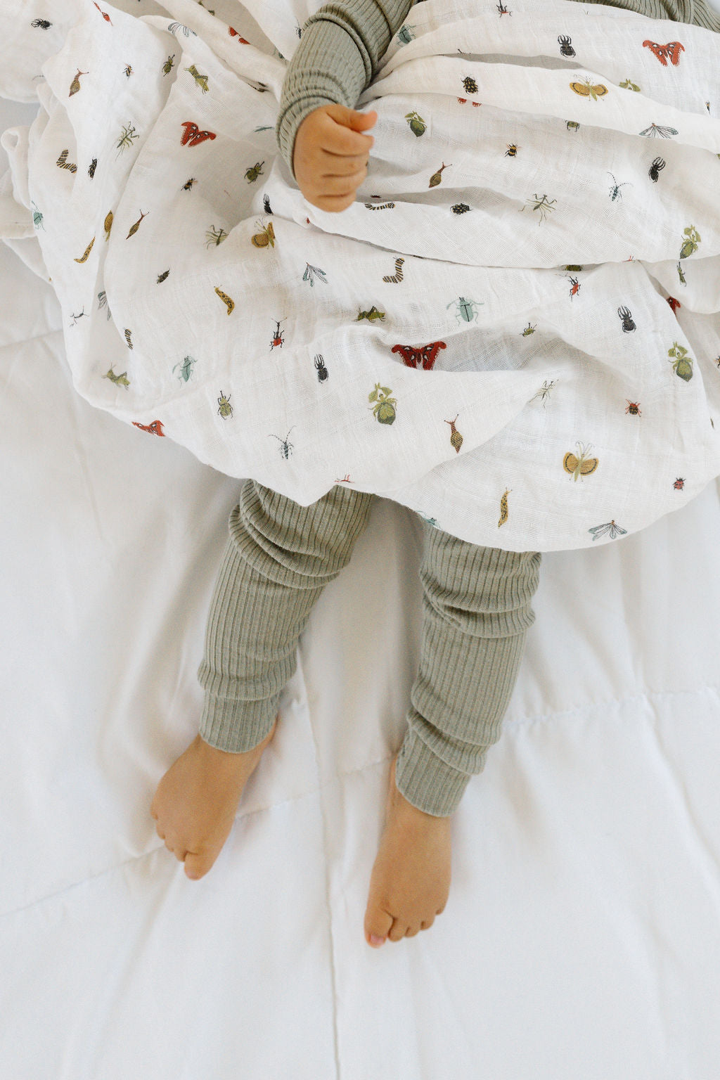 White animal-print baby swaddle blanket, wrapped around infant’s legs