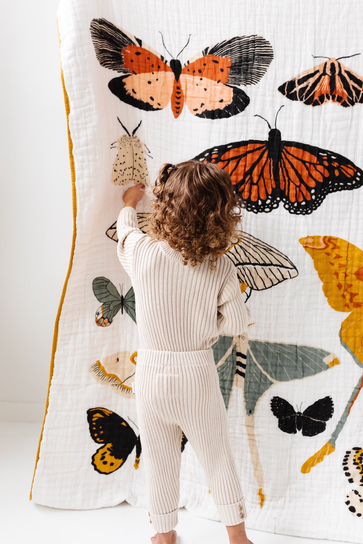 White quilted throw blanket with large orange and black butterfly prints, mustard edge