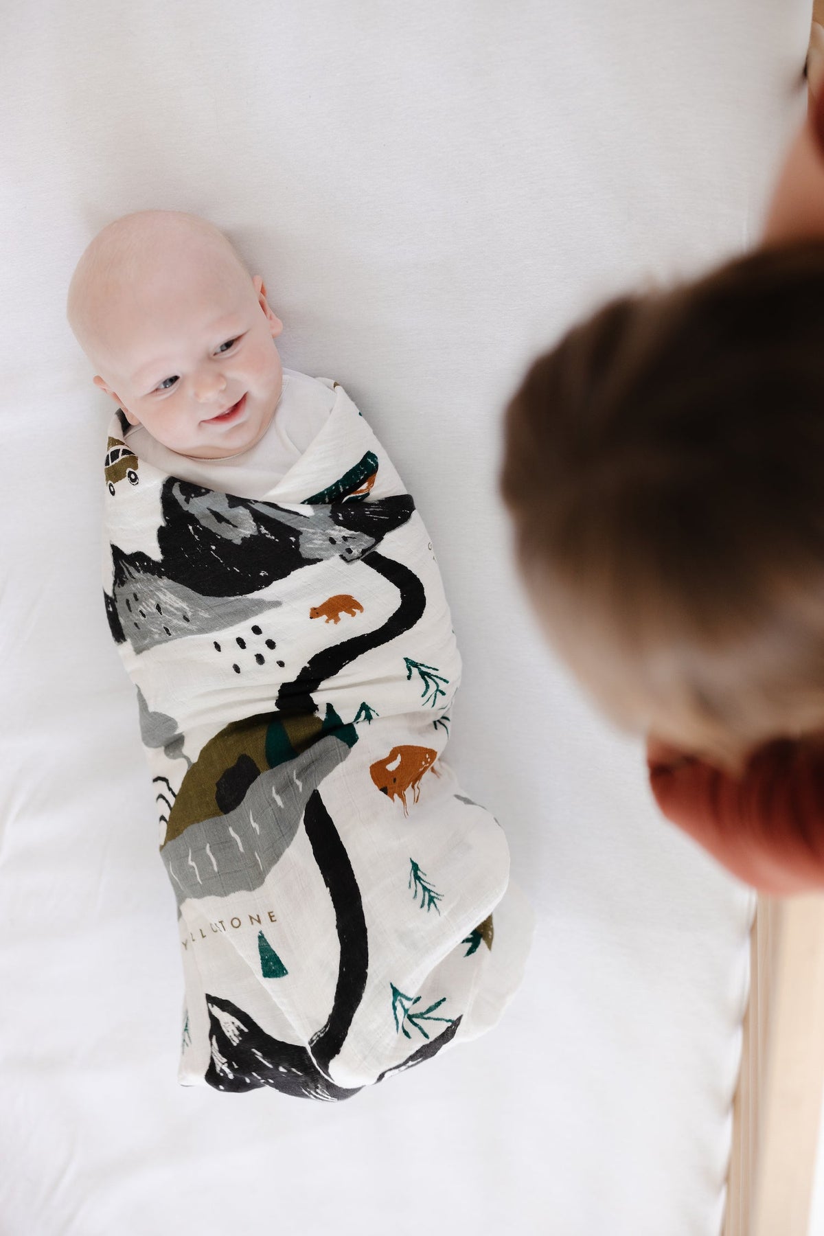 Baby swaddle blanket, white with black bear graphic and mountain trail map print
