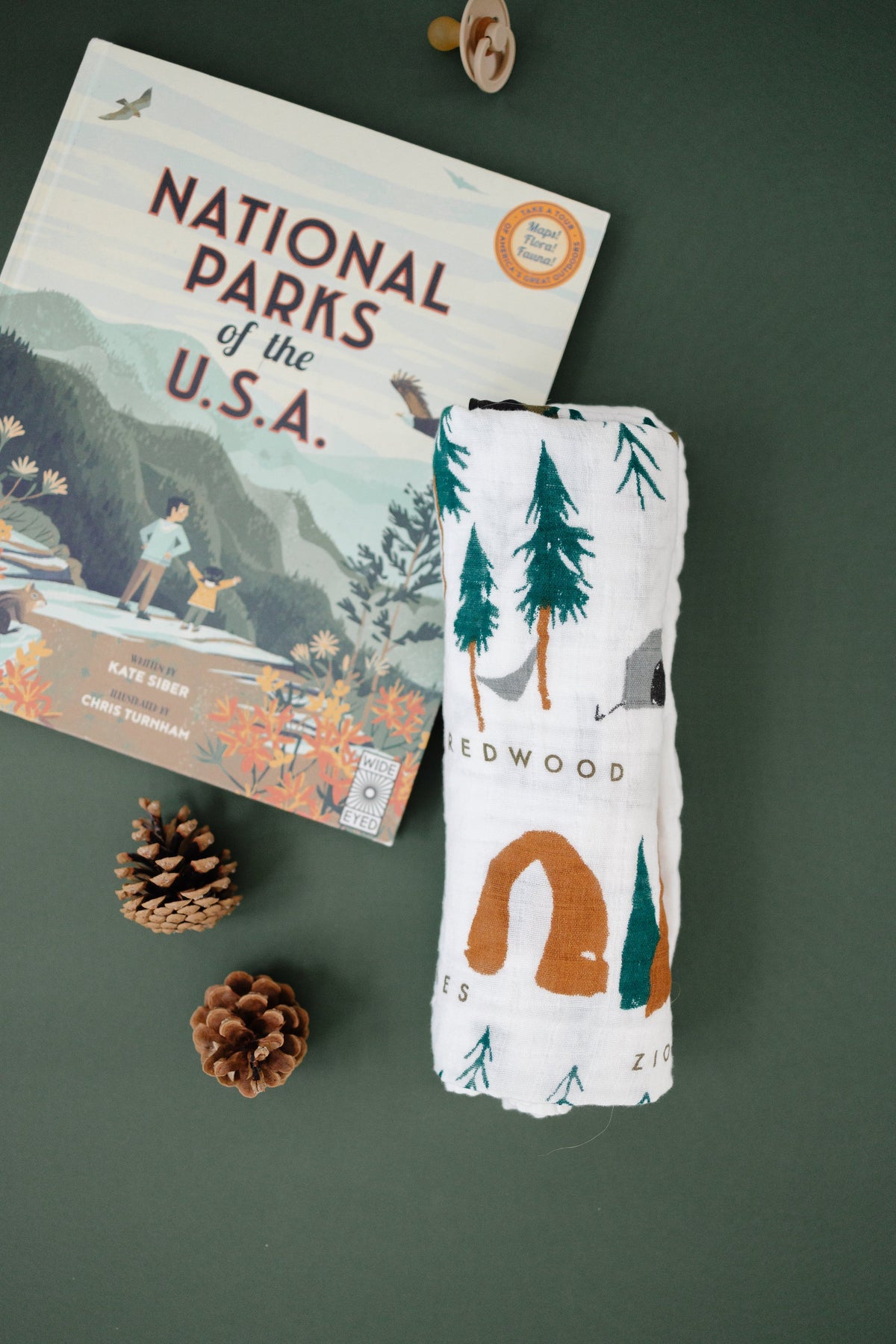 Baby swaddle blanket, white with tree and desert canyon print, folded with tag