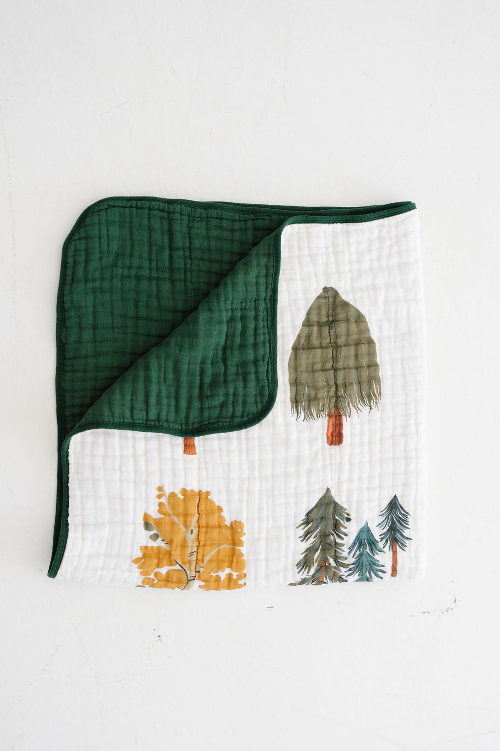 Forest trees quilt folded, green border and tree prints on white