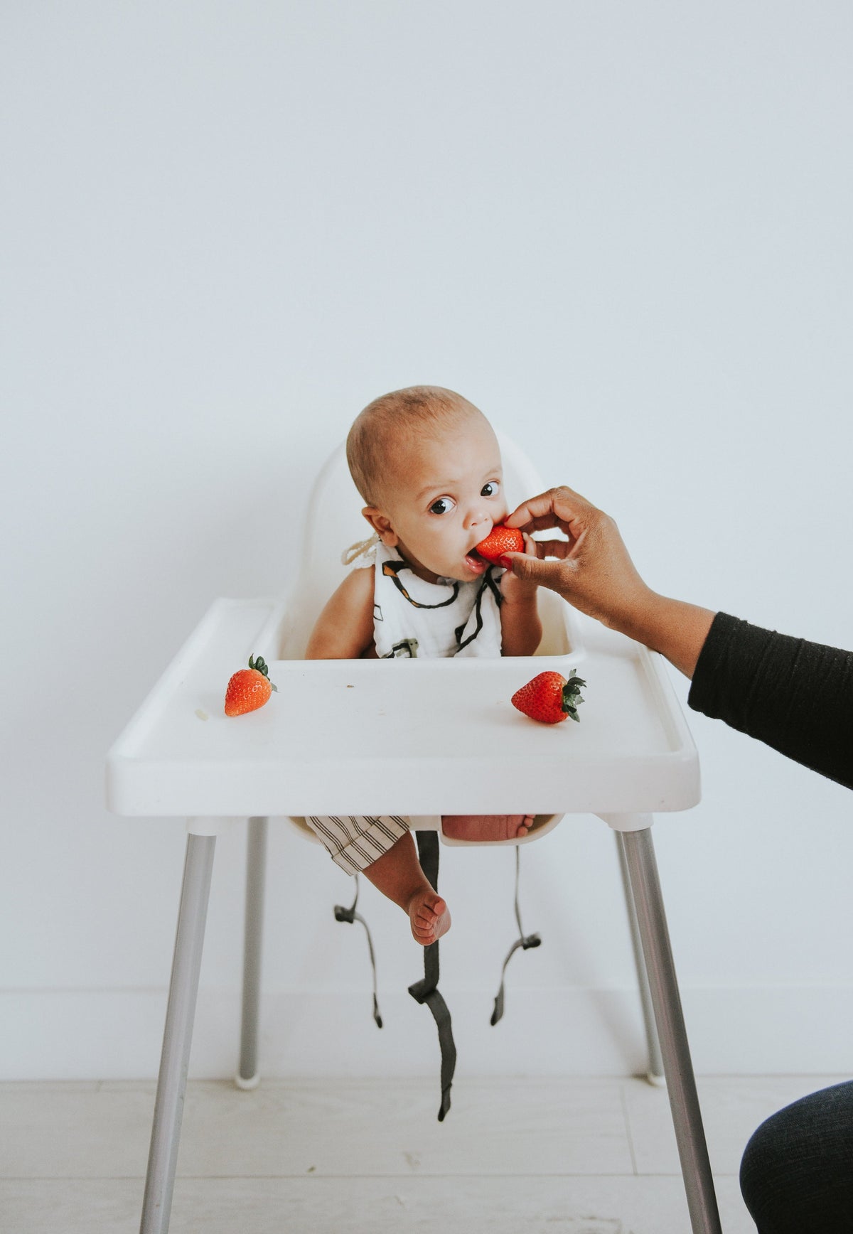 Baby wearing animal print bib with dog and cat icons during feeding