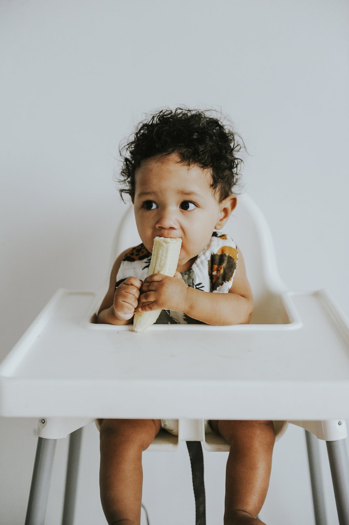 Baby in animal print bib with dog and cat illustrations; hand near mouth