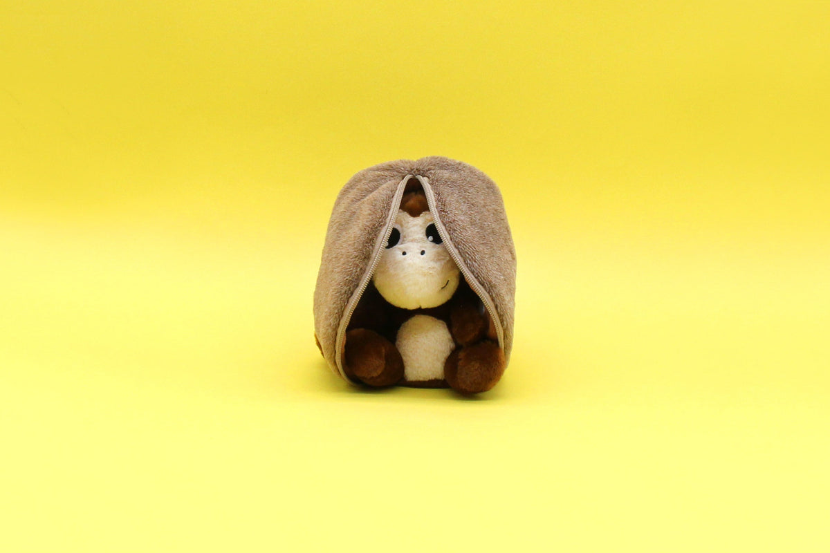 Light-faced plush peeking from beige rounded hood pouch