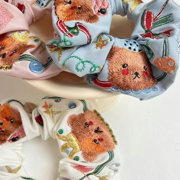 Light blue scrunchie with embroidered circus bear faces and star-and-ribbon details