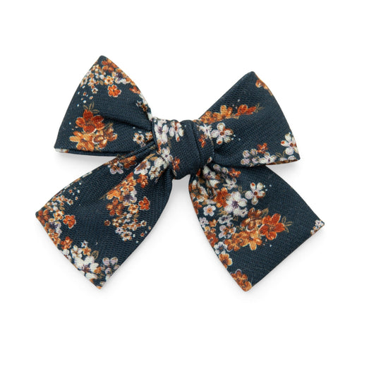 Petite hair bow in dark navy with orange and cream floral print, bow tie style