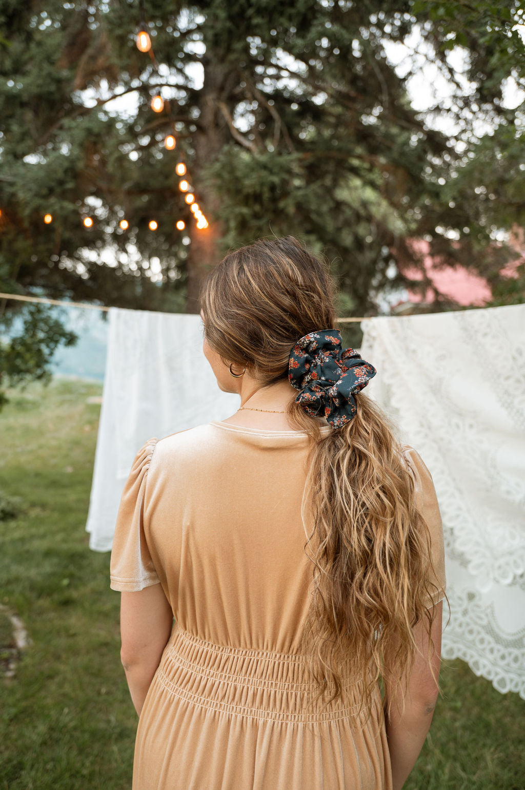 Floral hair scrunchie worn on long blonde hair, dark navy with orange blooms